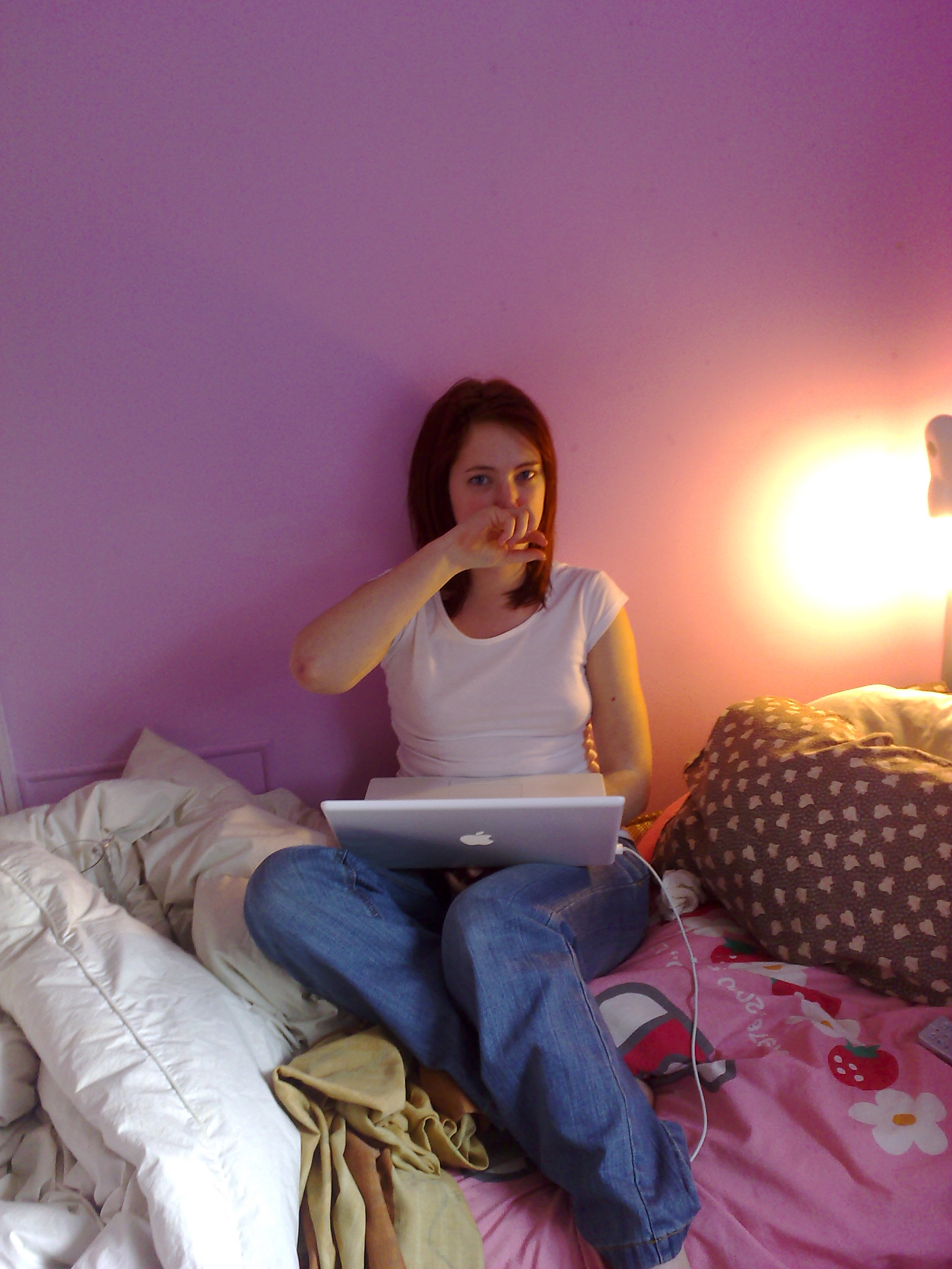 a woman sitting on a bed with a laptop