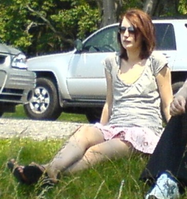 two people sitting on the grass near a car