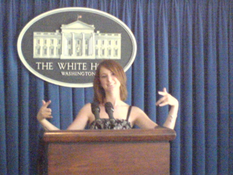 a woman standing at a podium with her hands up