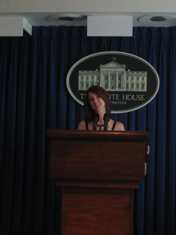 a woman standing at a podium in front of a blue curtain