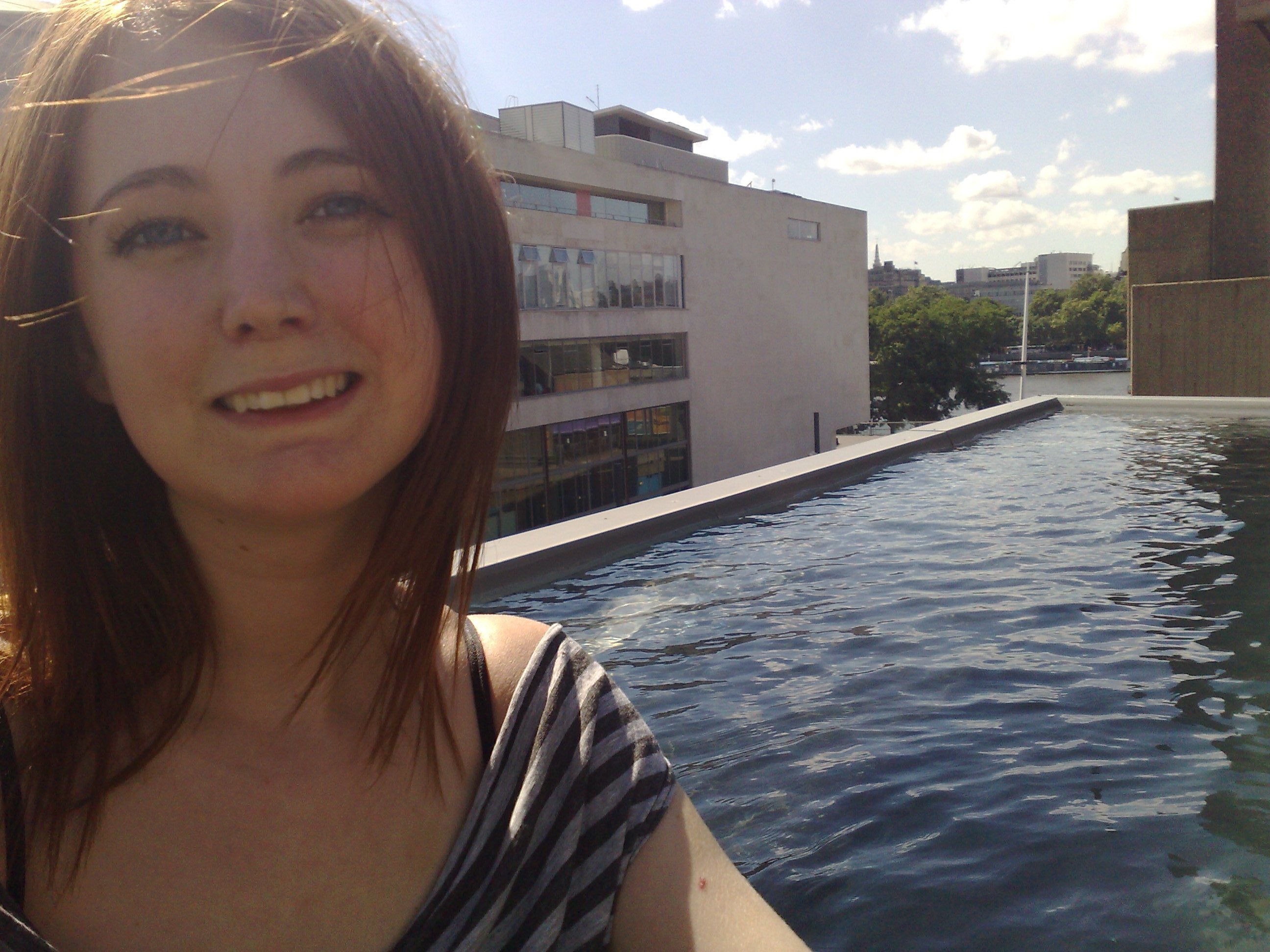 a woman standing in a pool with a building in the background Se