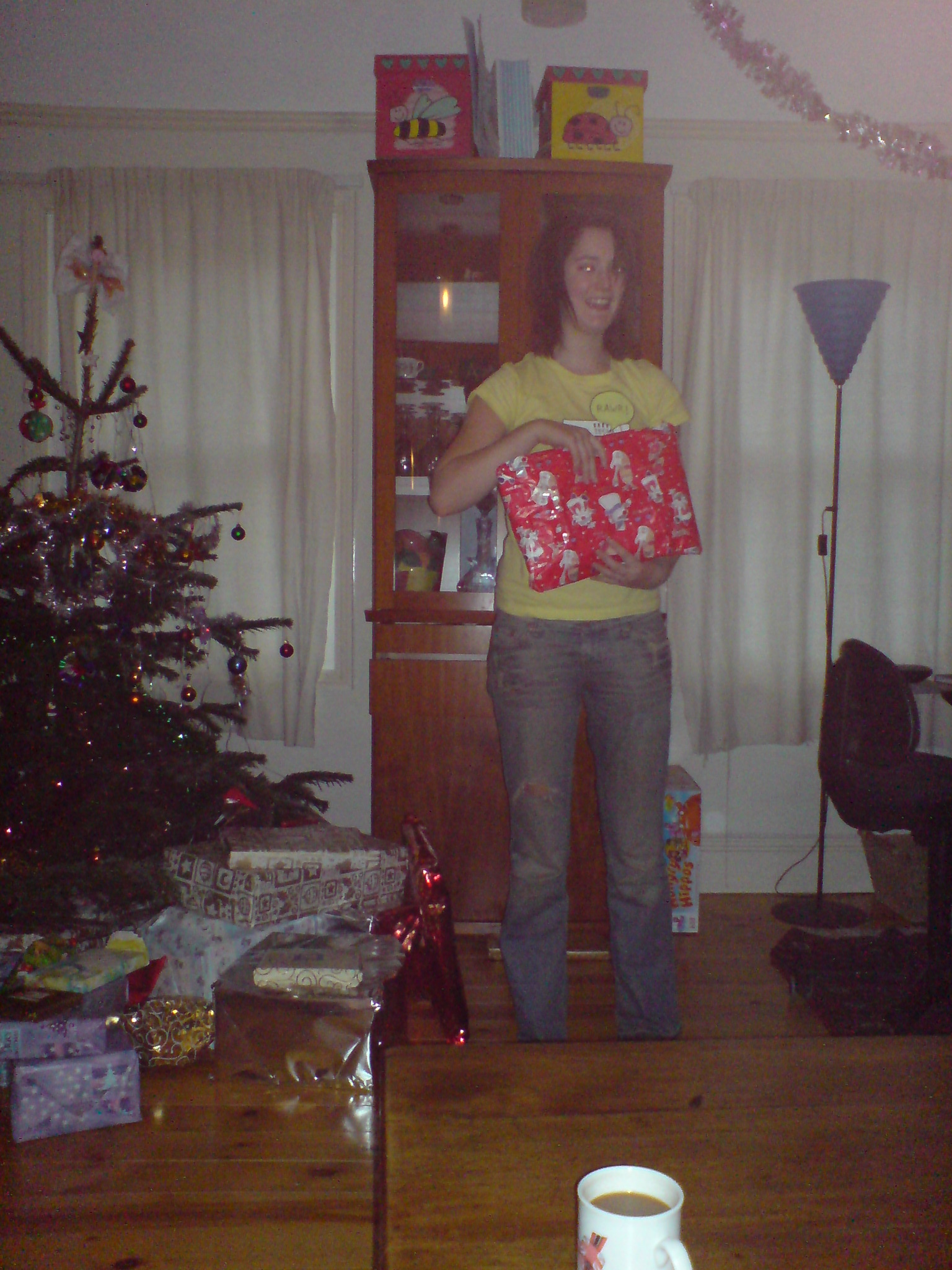 a woman standing in a living room with a christmas tree