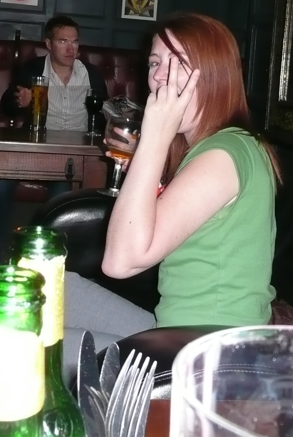 a woman sitting at a table with a bottle of beer