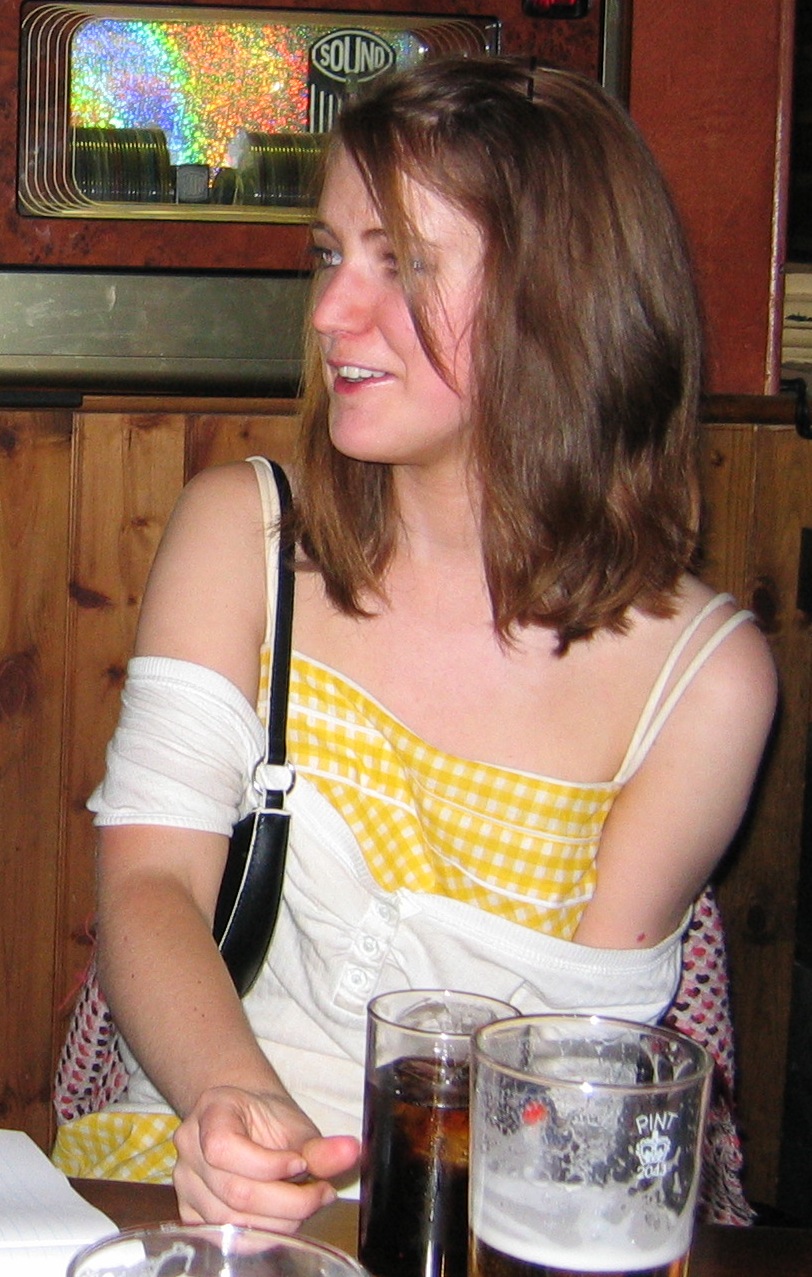 a woman sitting at a table with a glass of beer