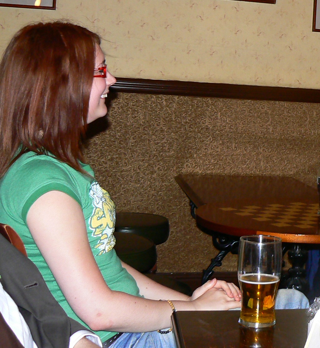 a woman sitting at a table with a glass of beer