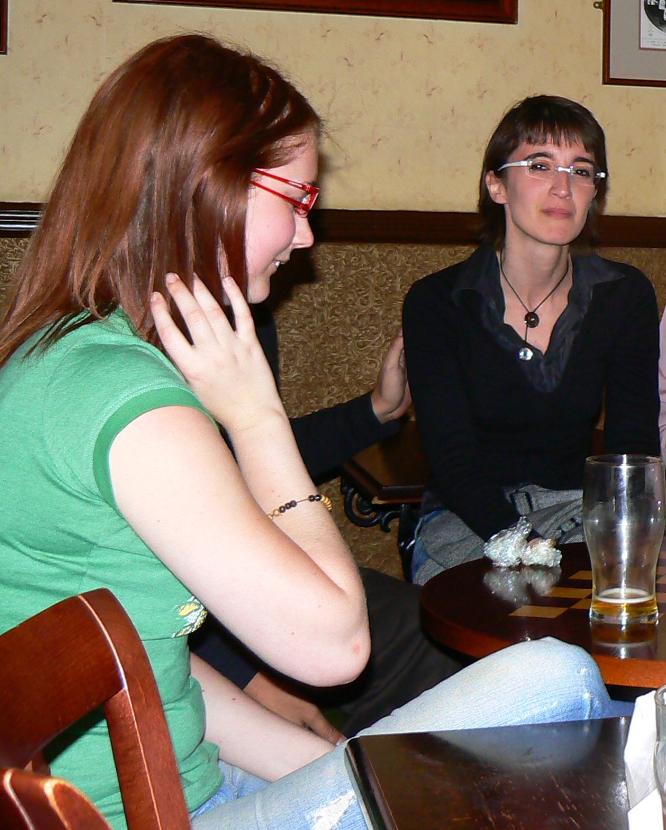 a woman sitting at a table with a glass of beer