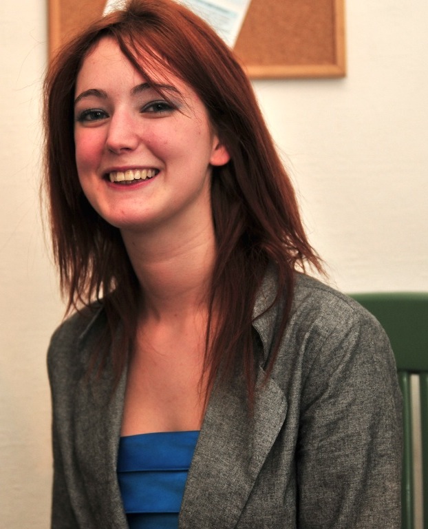 a woman sitting on a green chair in front of a wall