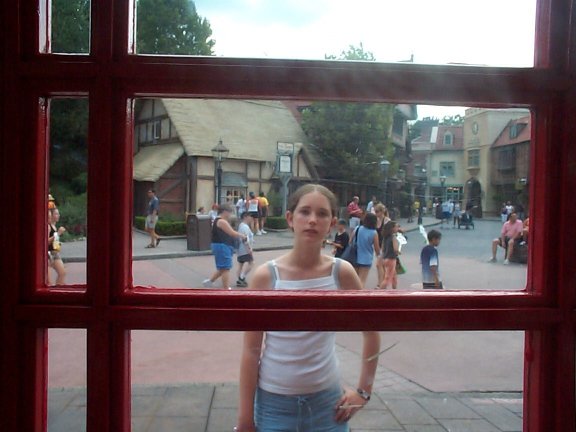 a girl standing in front of a red phone booth