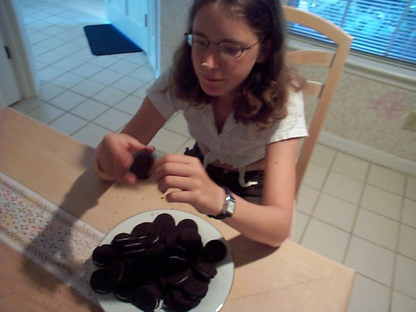 a woman sitting at a table with a plate of chocolate covered cookies