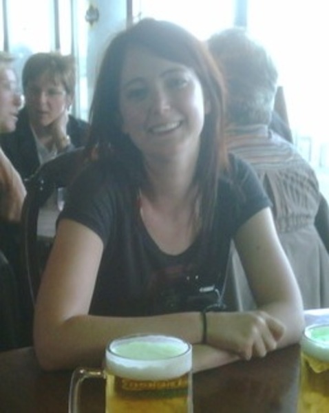 a woman sitting at a table with two beer glasses