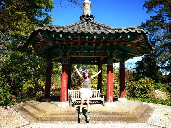 a woman in a white dress standing in front of a red and green pagoda