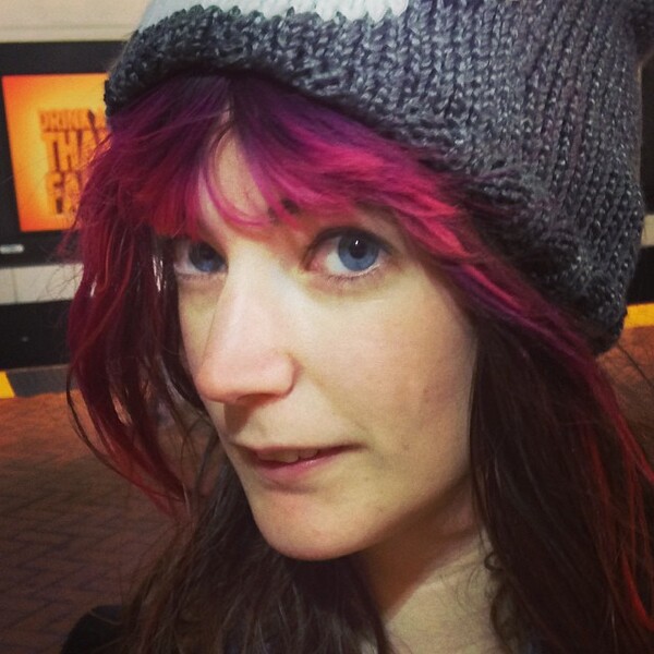 a woman with red hair wearing a knit hat