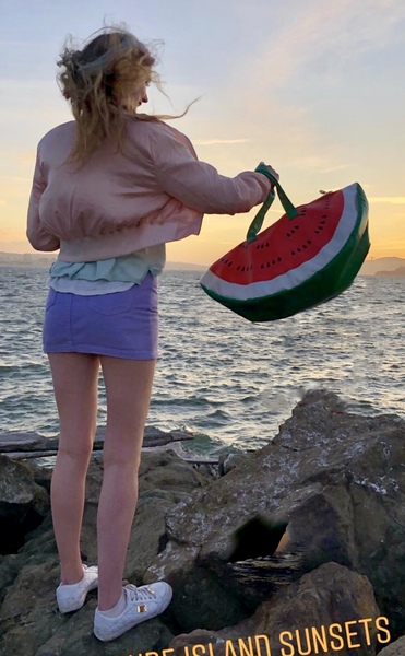 a woman standing on a rock with a watermelon