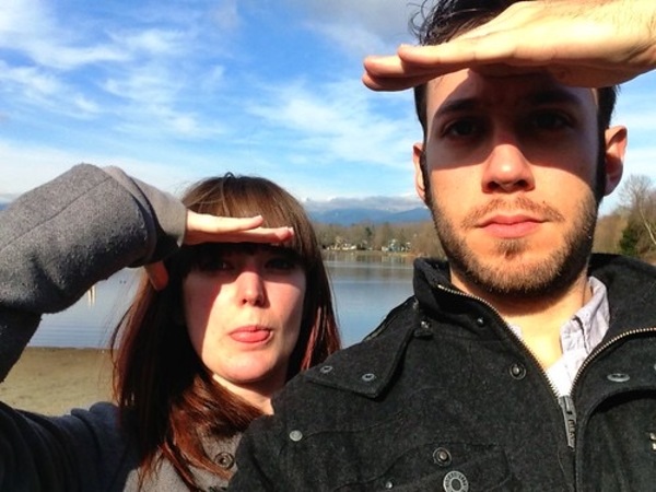 a man and woman are standing near a lake