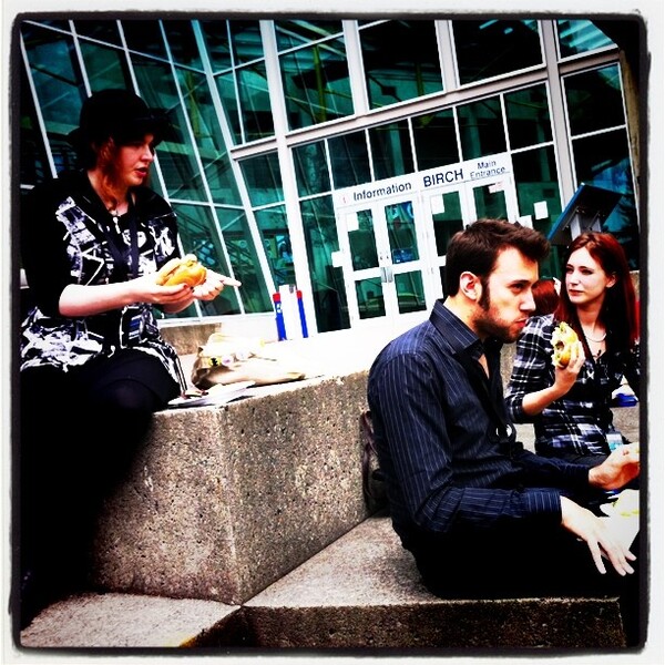 a man and woman sitting on a ledge eating food