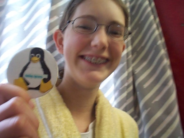 a girl in glasses holding a penguin pin