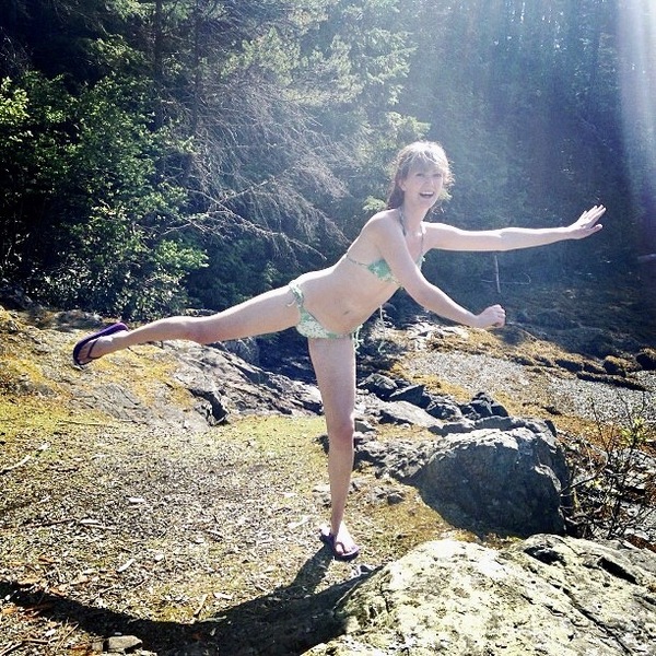 a woman in a bikini is standing on rocks