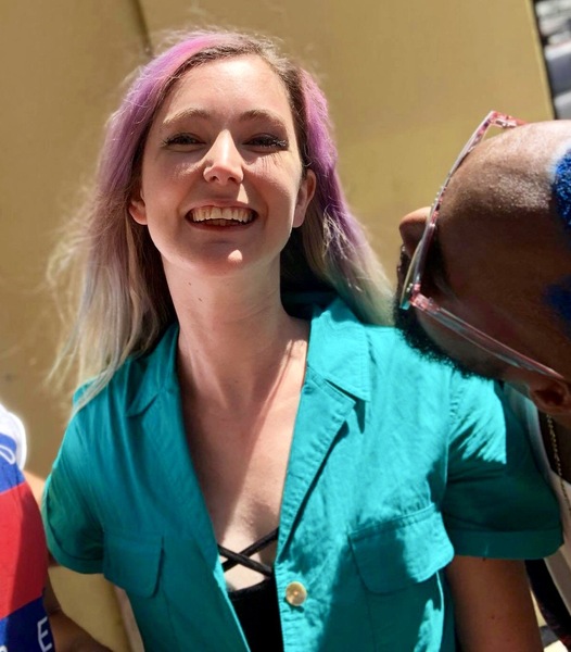 a woman with purple hair and glasses is smiling