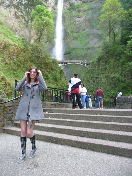 a woman is standing on the steps in front of a waterfall