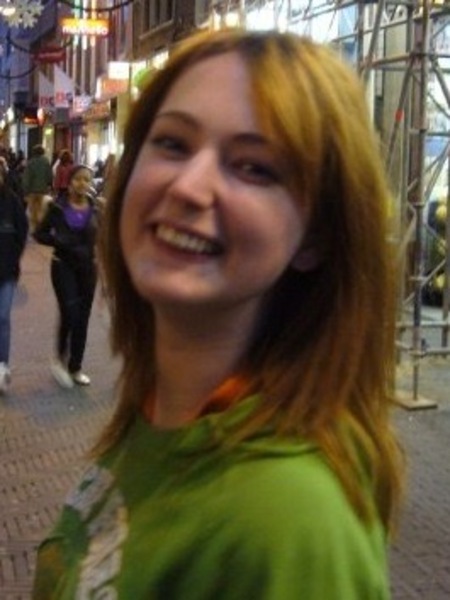 a woman standing in a crowded street with a man walking by