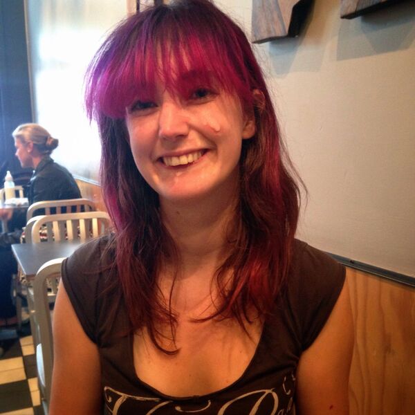 a woman with red hair sitting at a table seen han