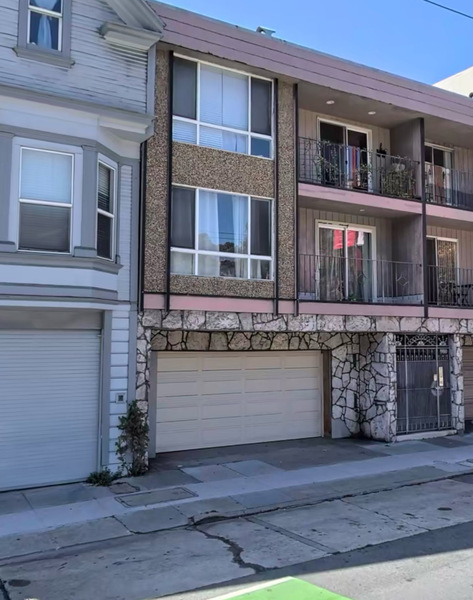 a two story apartment with a garage and garage doors