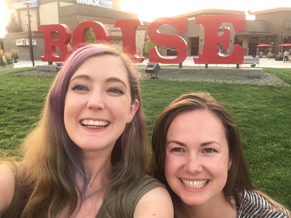 two women posing for a photo in front of a sign