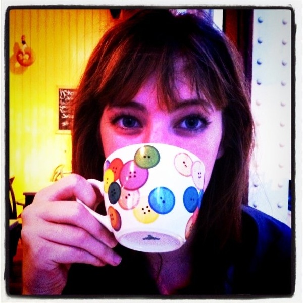 a woman holding a cup with buttons on it