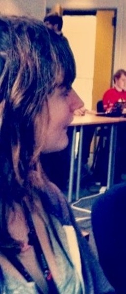 a woman with long hair sitting in a classroom