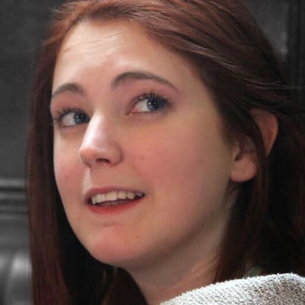 a woman with long red hair and a white sweater