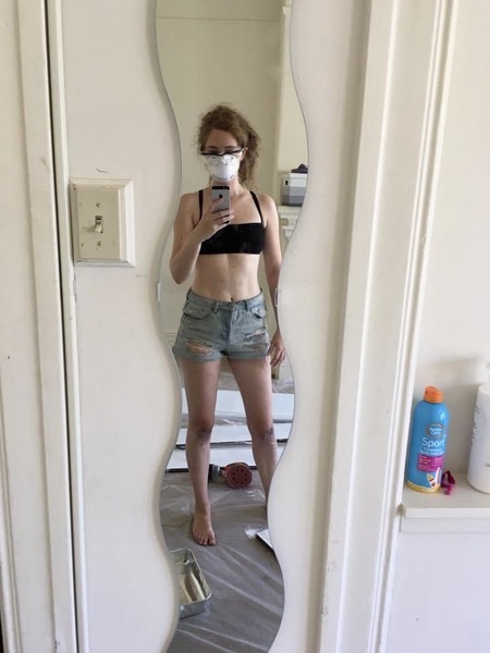 a woman in shorts and a black bra top is taking a selfie