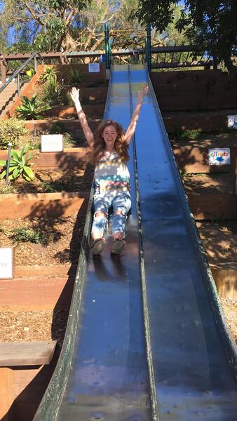 a young girl is sliding down a slide