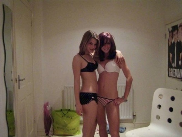 two women in underwear standing on a bed