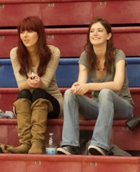 two women sitting on a bleacher