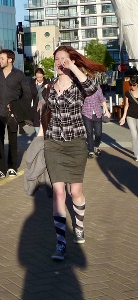 a woman walking down a sidewalk while talking on a cellphone