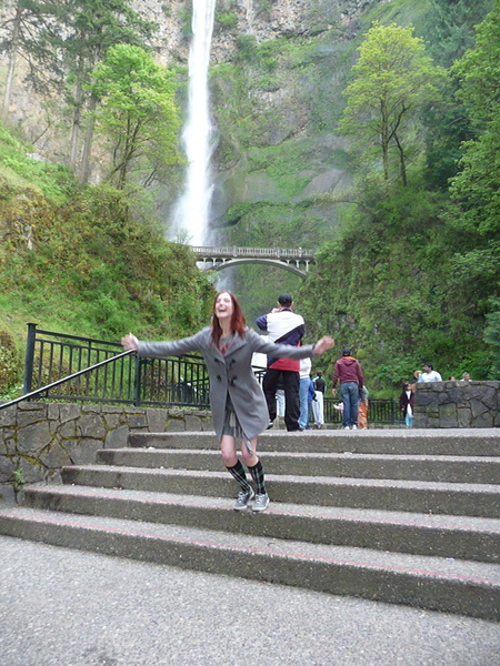 a woman is standing on some steps near a waterfall