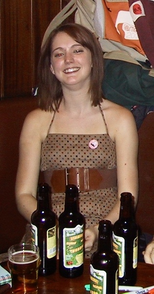 a woman sitting at a table with a bunch of beer bottles