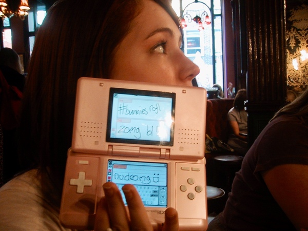 a woman holding a pink nintendo game console