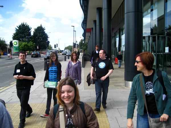 a group of people walking down a sidewalk Lit
wh
‘or

sig
. <
seseee ee