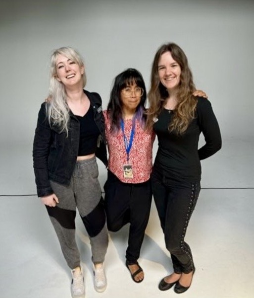 three women standing in front of a white background