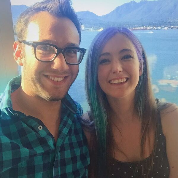 a man and woman posing for a photo in front of a lake