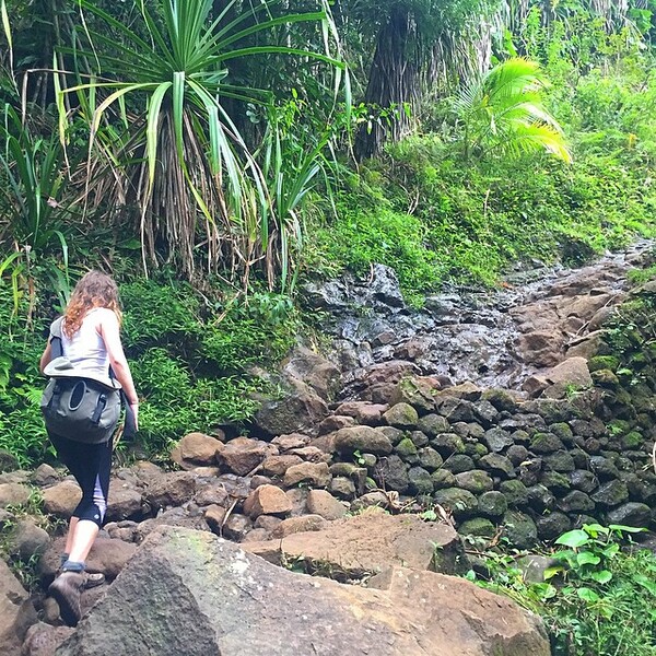 a woman walking down a rocky path in the jungle