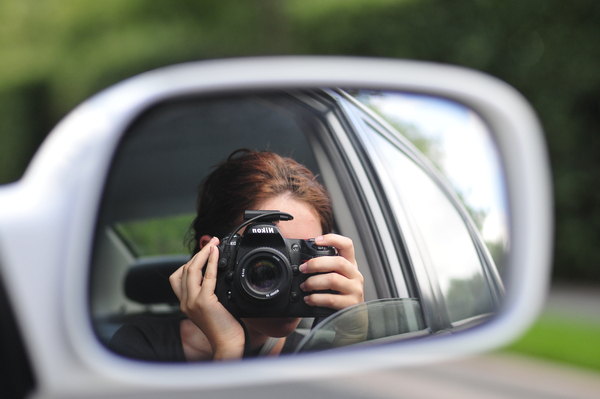 a woman taking a picture of herself in a car mirror