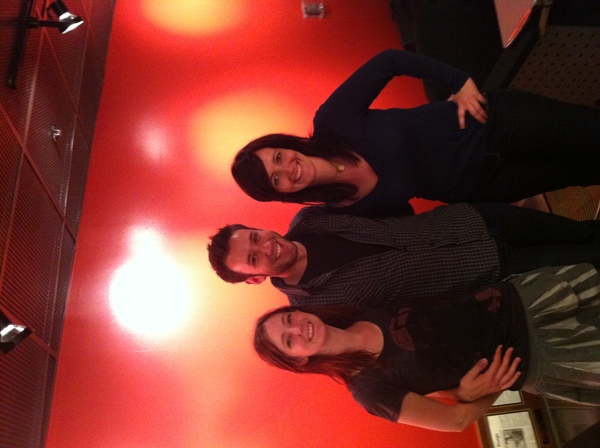 two people standing in a room with a red floor Pay