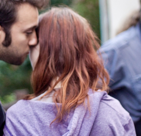 a man and woman kissing in front of a building