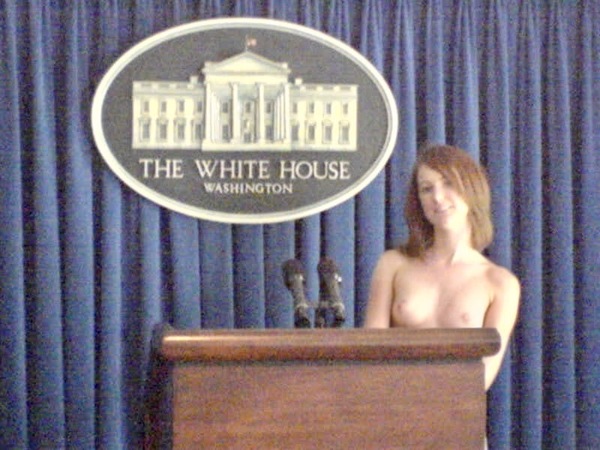 a naked woman standing at a podium in front of a blue curtain