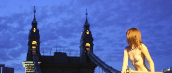 a woman standing on a roof with a clock tower in the background