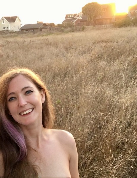 a woman with purple hair and a white shirt is standing in a field