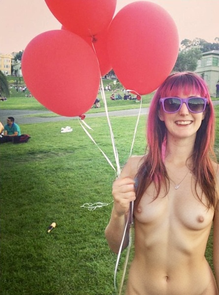 a woman with pink hair holding red balloons