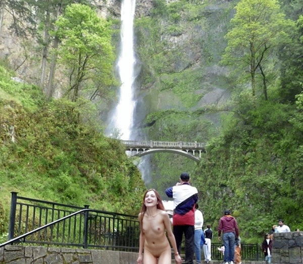 a naked woman standing in front of a waterfall